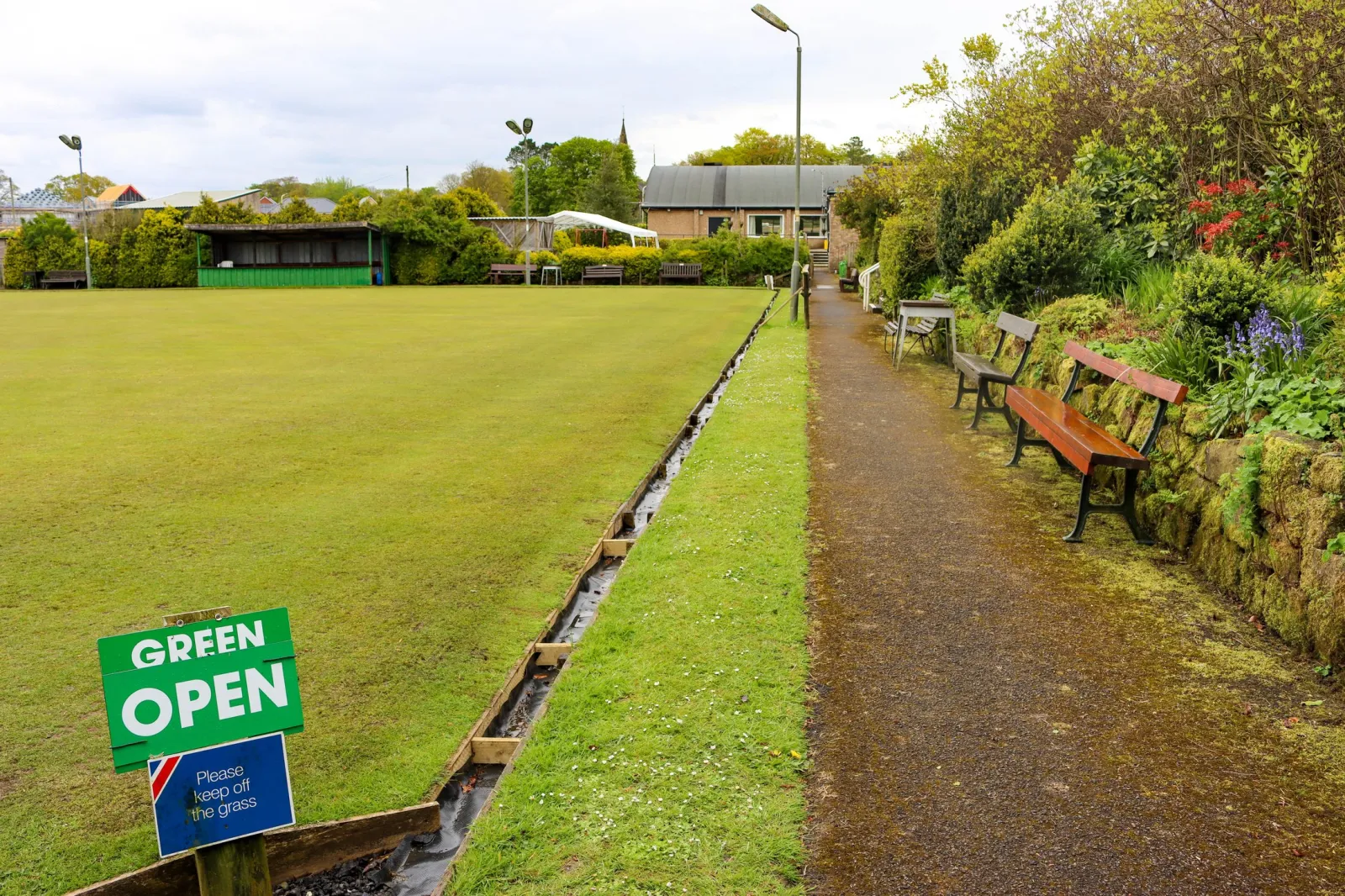The clubhouse seen across Whittingham Club's bowling green, with a 'GREEN OPEN' sign in the foreground
